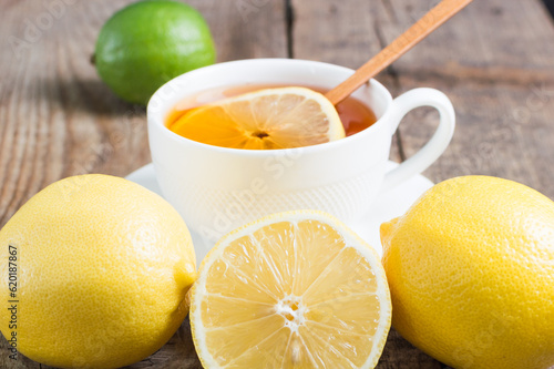 Tea for cold and flu with natural ingredients. Black tea with lemon and lime on wooden background.