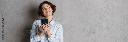 Fotografie Young brunette woman smiling and using mobile phone