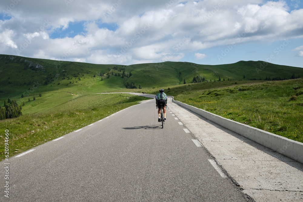 Obraz premium Male cyclist on a gravel bike is riding on the road in the hills with a view of the mountains.Sport motivation image. Cycling holiday in Romania. 