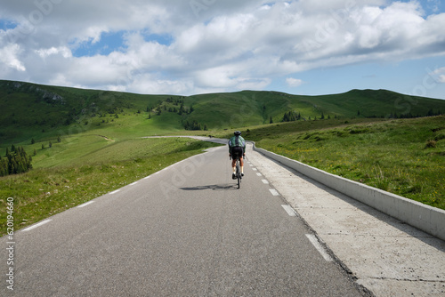 Male cyclist on a gravel bike is riding on the road in the hills with a view of the mountains.Sport motivation image. Cycling holiday in Romania. 