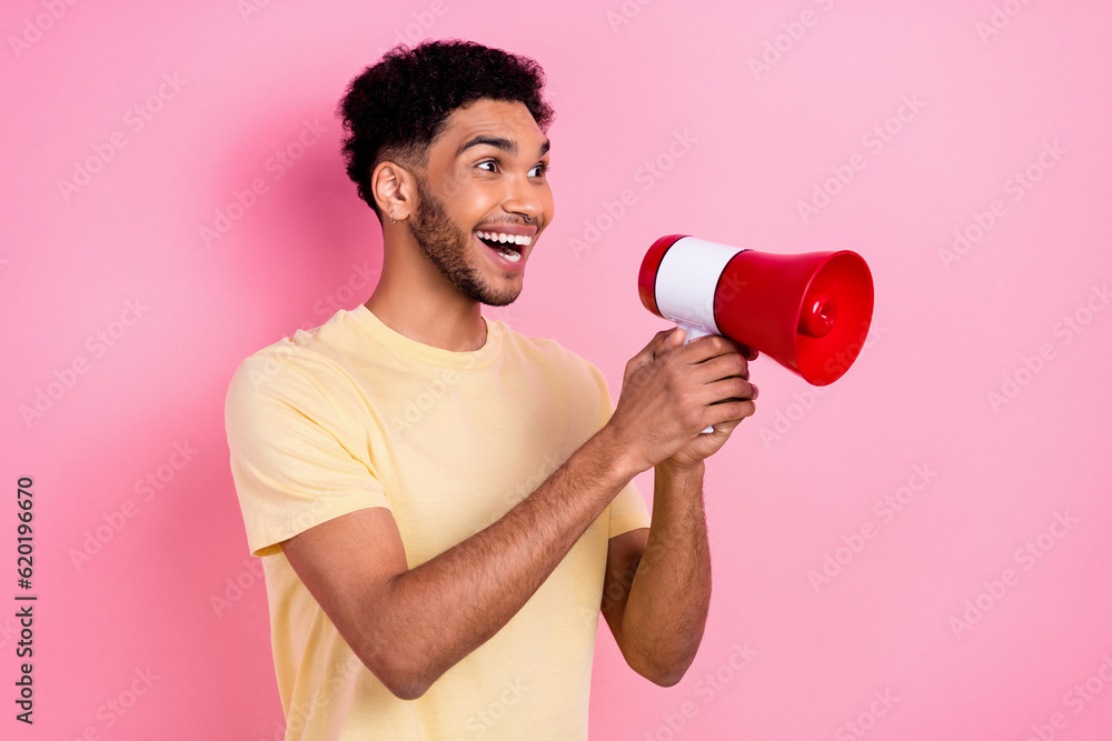 Portrait of impressed excited astonished man dressed yellow t-shirt hold loudspeaker shout empty space isolated on pink color background Portrait of impressed excited astonished man dressed yellow t-shirt hold loudspeaker shout empty space isolated on pink color background
