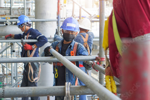 Worker's hand holding iron to installation scaffolding work for support building construction site of petrochemical plant, oil and gas plant.