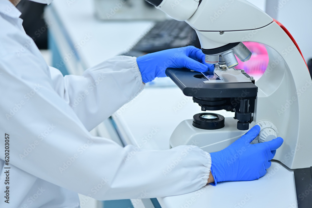 Medical Science Laboratory: Portrait of a scientist looking under a microscope without analyzing a test sample. Ambitious young biotechnologist working with advanced equipment. Medical Science Laboratory: Portrait of a scientist looking under a microscope without analyzing a test sample. Ambitious young biotechnologist working with advanced equipment.