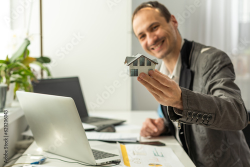 Happy elegant caucasian business man, manager, director, sits at a desk in the office, talking on the phone with a colleague or client, putting his legs on the table, making an appointment, smiling