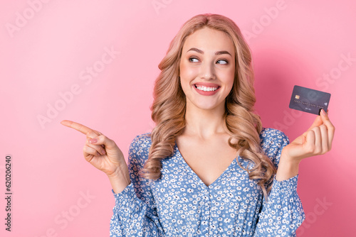 Portrait of young woman wear flowers print blouse plastic universal bank payment point finger novelty ad isolated on pink color background photo