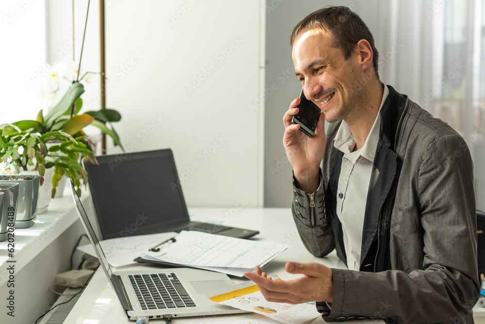 Happy successful busy caucasian man in a suit, company employee, top manager, boss, sitting in the office, talking on the phone with a colleague or client, resolves work issues, smiling Happy successful busy caucasian man in a suit, company employee, top manager, boss, sitting in the office, talking on the phone with a colleague or client, resolves work issues, smiling