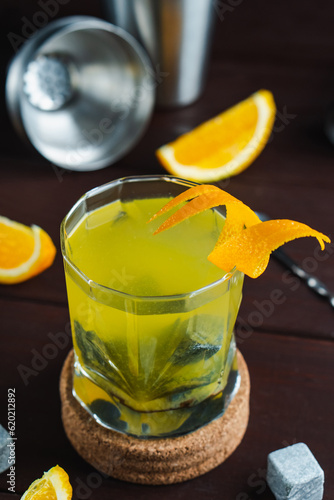 Whiskey cocktail in glass with natural cube stones and orange peel. Jagger and shaker at background photo