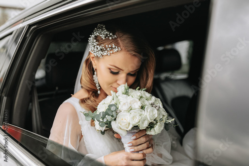 close-up portrait of a rather shy bride in a car window looking at her bouquet of flowers