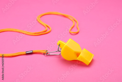 One yellow whistle with cord on pink background