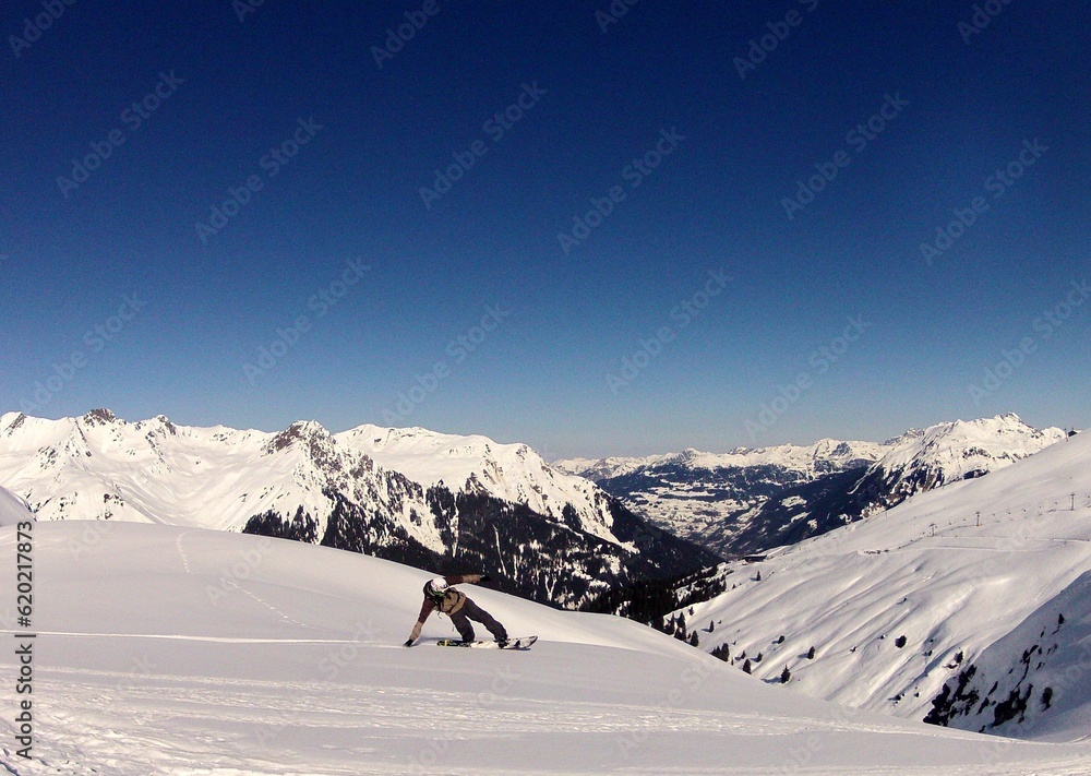 snowboarders in snow with sun and blue sky with clouds