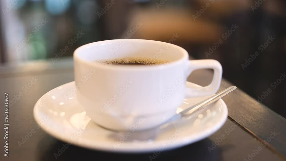 White coffee cup with hot steam lies on black wooden table White coffee cup with hot steam lies on black wooden table