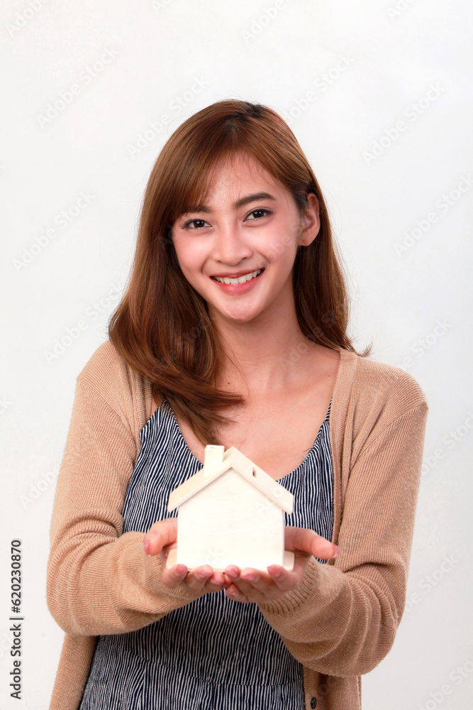 Woman's hand holding wooden house mockup on gray background Woman's hand holding wooden house mockup on gray background
