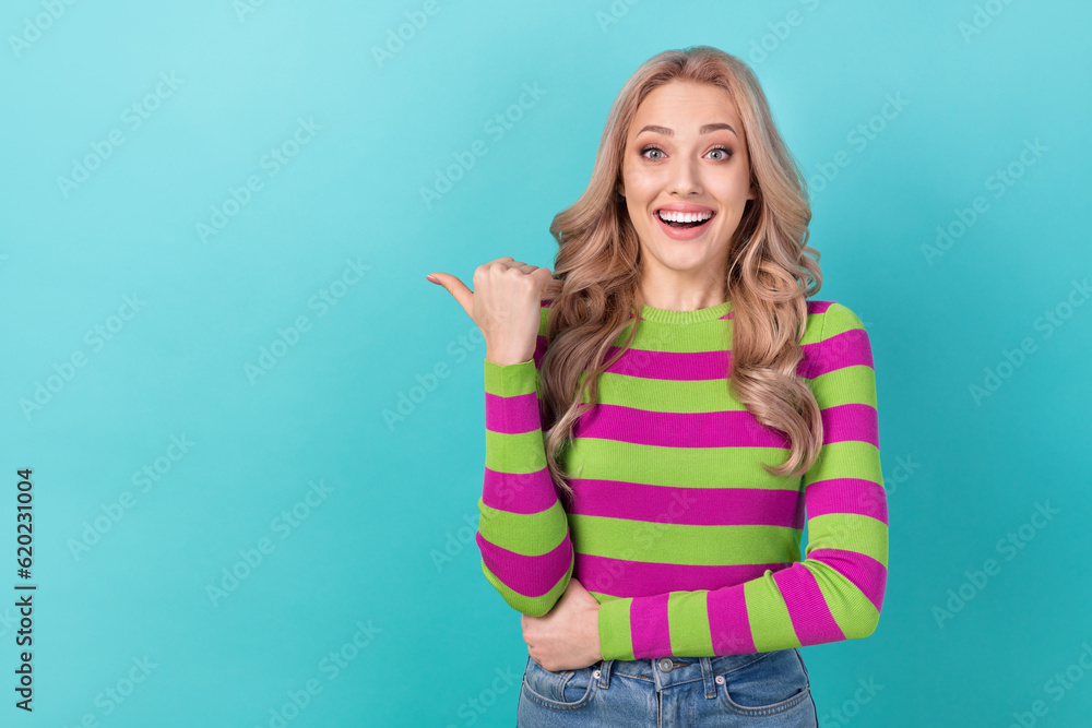 Photo portrait of lovely young lady excited finger point empty space wear trendy striped garment isolated on cyan color background Photo portrait of lovely young lady excited finger point empty space wear trendy striped garment isolated on cyan color background