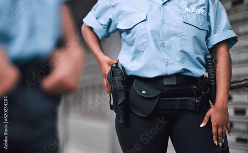Hand, gun and security with a guard on duty or patrol in the city for safety and law enforcement. Police, service and armed response with an officer outdoor in an urban town for crime prevention