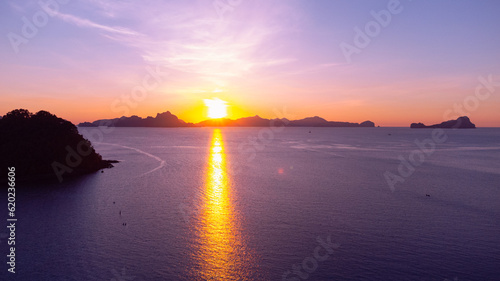 Piękny zachód słońca, kolorystyka różowo pomarańczowa, tropikalne wyspy i ocean.