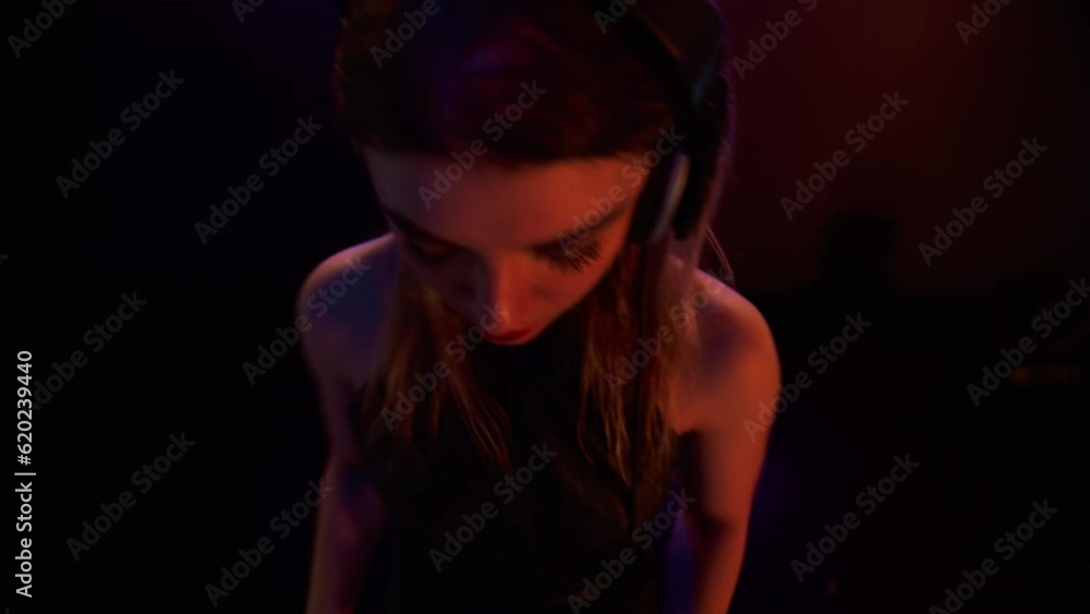 Portrait of attractive female techno DJ performing playing her music set on a stage of a nightclub or during a festival Portrait of attractive female techno DJ performing playing her music set on a stage of a nightclub or during a festival