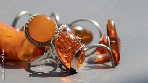 Different shiny Baltic amber rings in silver close up. Isolated vintage amber jewelry on a gray background. Macro.