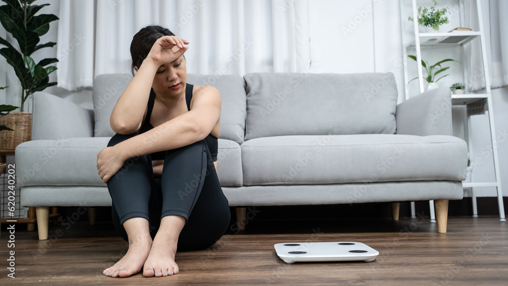 Asian healthy woman bored of dieting Weight loss fail Fat diet and scale sad asian woman Upset on weight scale at home weight control. Asian healthy woman bored of dieting Weight loss fail Fat diet and scale sad asian woman Upset on weight scale at home weight control.