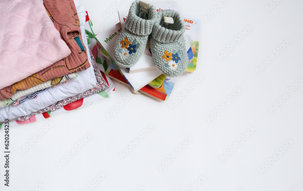 Box with baby stuff and accessories for newborn on bed. Gift box with knitted blanket, clothes, socks, shoes and toy. Baby shower concept. Flat lay, top view