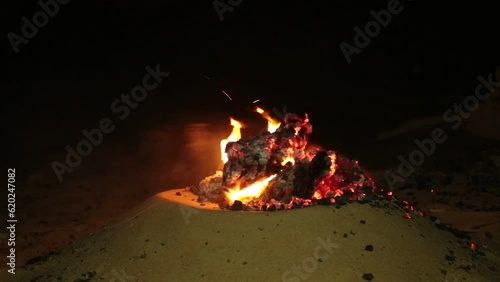 camp fire bonfire aflame blazing in desert sand 