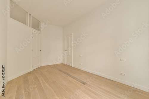 an empty room with white walls and wood flooring on the right, there is a door leading to another room