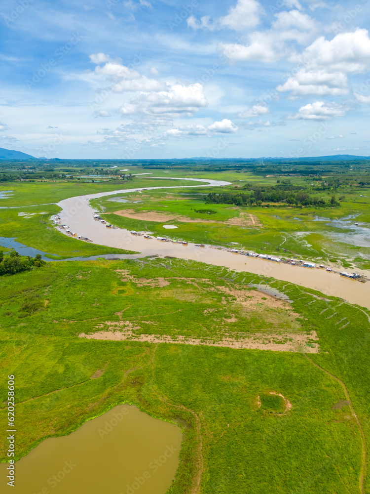Naklejka premium Aerial view of National Route 20 in Dong Nai province, group of floating house on La Nga river, Vietnam with hilly landscape and sparse population around the roads.