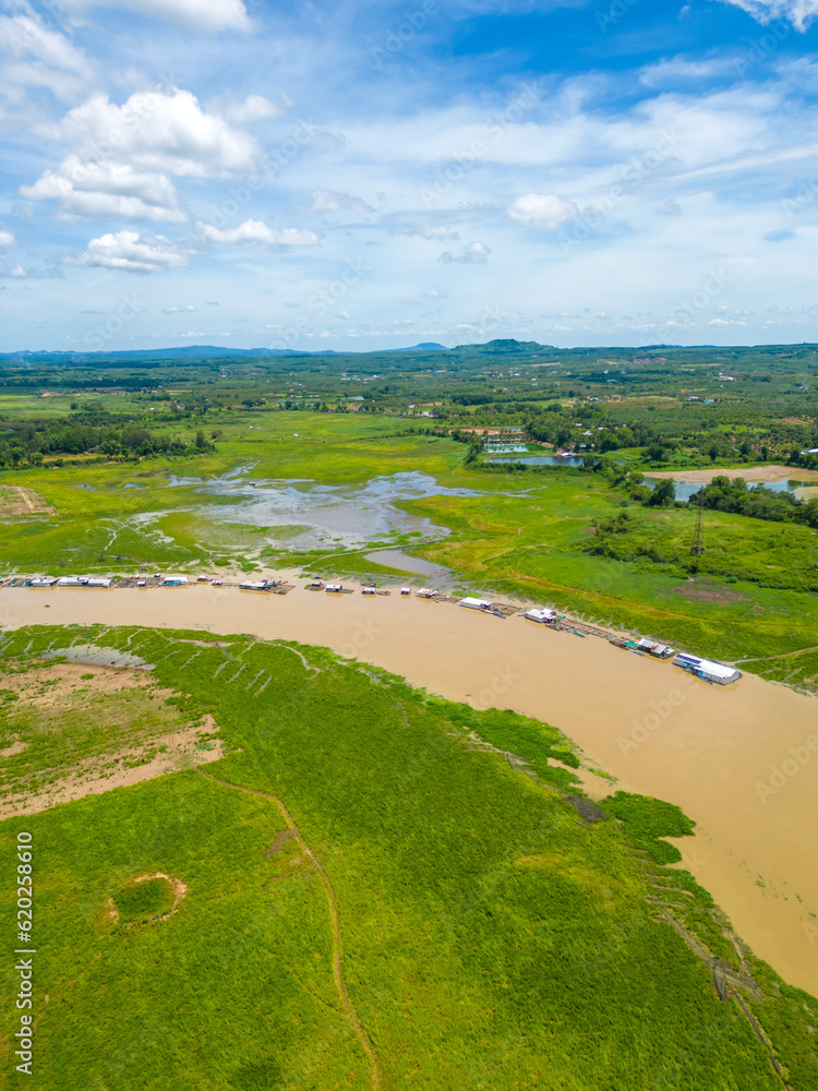 Aerial view of National Route 20 in Dong Nai province, group of floating house on La Nga river, Vietnam with hilly landscape and sparse population around the roads.