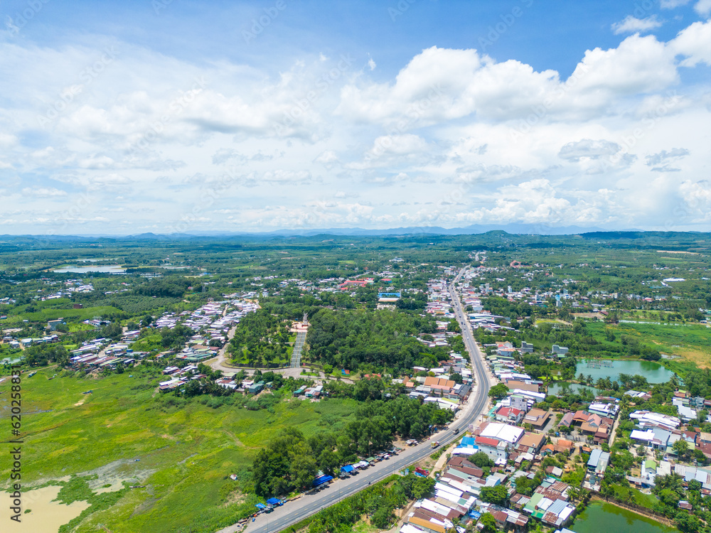 Aerial view of National Route 20 in Dong Nai province, group of floating house on La Nga river, Vietnam with hilly landscape and sparse population around the roads.
