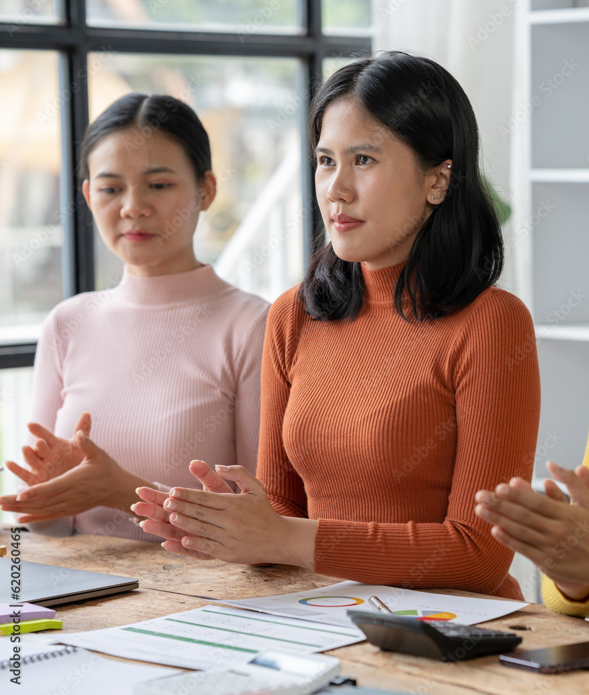 Acknowledging Success: A team of Asian businesswomen applauds a colleague during a meeting, showcasing teamwork and appreciation in a modern office setting. Acknowledging Success: A team of Asian businesswomen applauds a colleague during a meeting, showcasing teamwork and appreciation in a modern office setting.