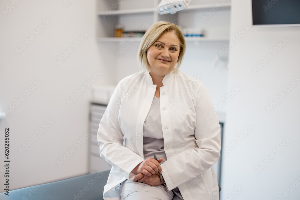 Portrait of mid adult nurse in medical gown at office. Beautiful caucasian medical worker with blonde hair at clinic Portrait of mid adult nurse in medical gown at office. Beautiful caucasian medical worker with blonde hair at clinic