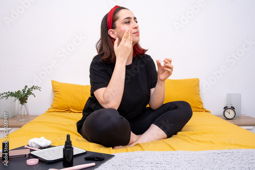 Cuidado de la piel al despertar: Mujer aplicando delicadamente crema hidratante en la cama