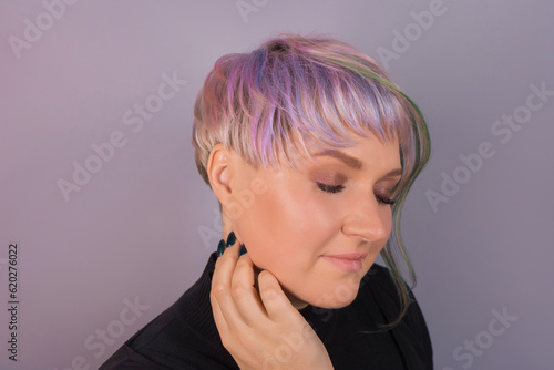 Portrait of cute European appearance of a pretty Caucasian woman posing with a hand near her face close-up with bob hairstyle and stylish colored, hair coloring on a studio background