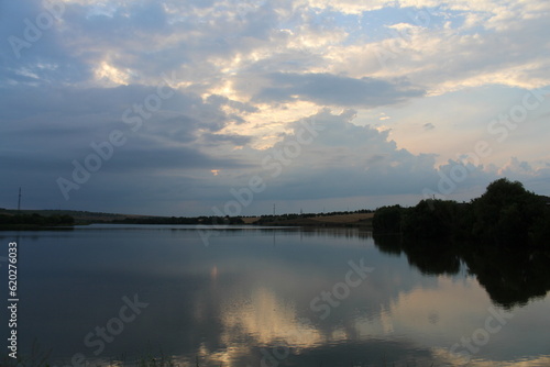 A body of water with trees and clouds in the sky
