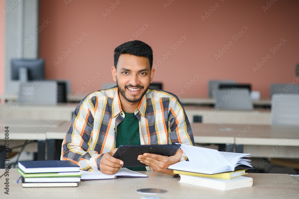 Handsome young Indian boy student with books and backpack at university. Education concept Handsome young Indian boy student with books and backpack at university. Education concept