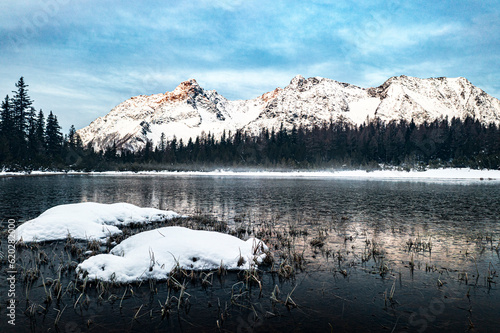 Snowy forest and mountains surrounding the frozen lake Entova, Valmalenco, Valtellina, Lombardy photo