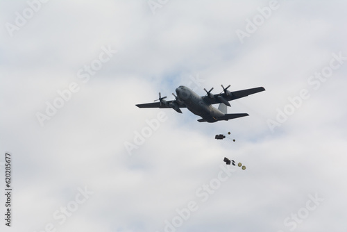 Obraz na plátně Military logistics transport plane dropping loads with parachutes, airdrop on a