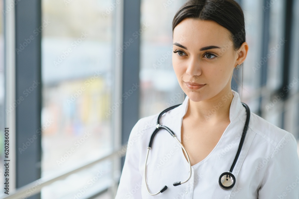Portrait of young female doctor standing in hospital corridor. Caucasian woman working in nursing home. Portrait of young female doctor standing in hospital corridor. Caucasian woman working in nursing home.