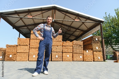 Fotografia Carpenter in uniform check boards on sawmill