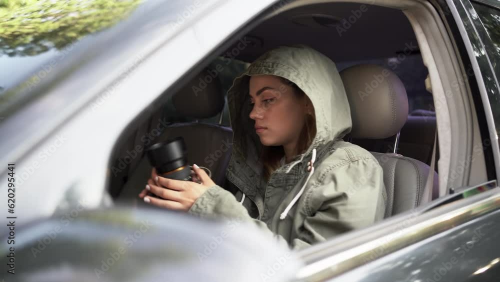 Female private detective or paparazzi with a camera sit in a car, takes photo of object of surveillance Female private detective or paparazzi with a camera sit in a car, takes photo of object of surveillance