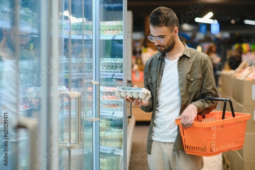 Male shopper chooses chicken eggs in a grocery supermarket photo