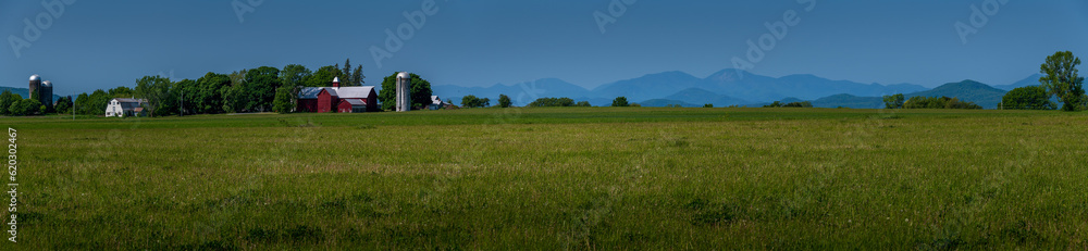 landscape with grass and sky Vermont countryside panorama rural red barn with lush green fields another side of Lake Champlain the Adirondack mountains are hazy from Canadian forest fires 