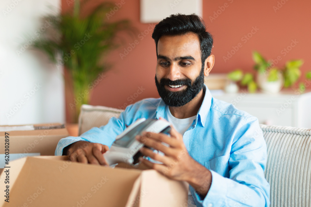 Happy Indian Buyer Guy Unpacking Box With Steamer At Home Happy Indian Buyer Guy Unpacking Box With Steamer At Home