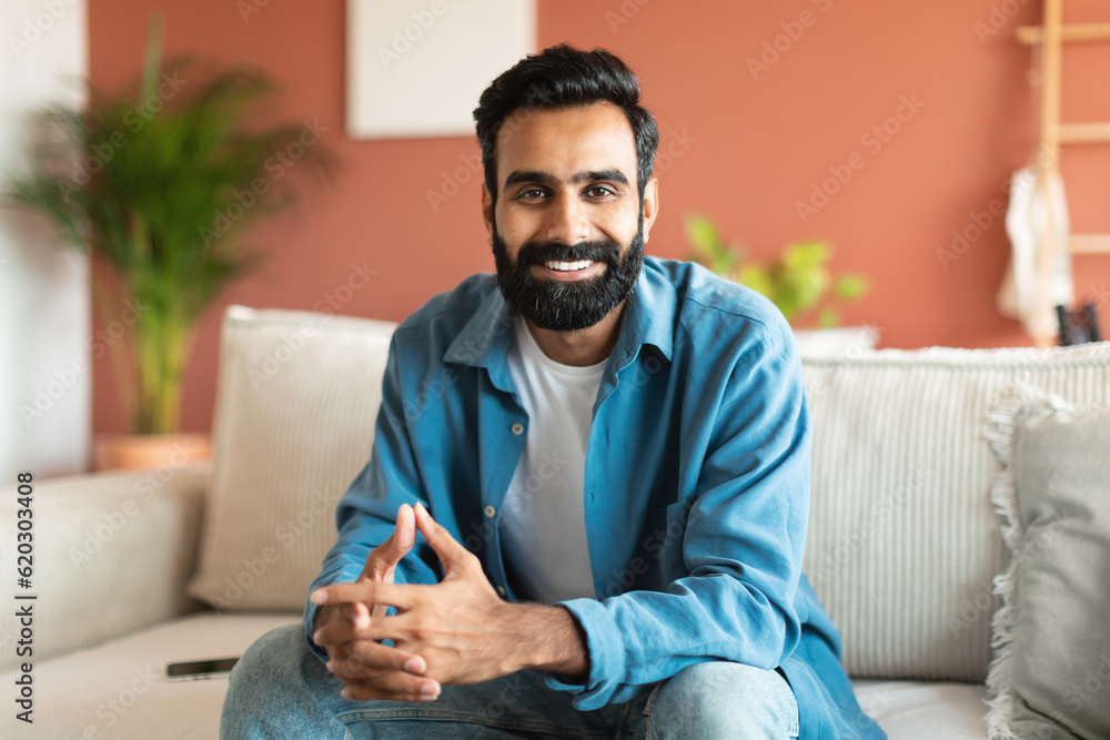 Lifestyle portrait of happy young indian man posing at home