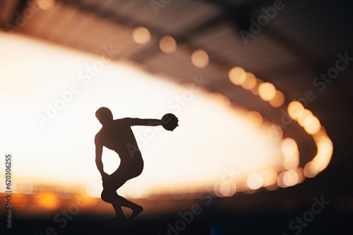 Quadro em tela Silhouette of Athlete, Discus Soaring in the Breathtaking Evening Glow