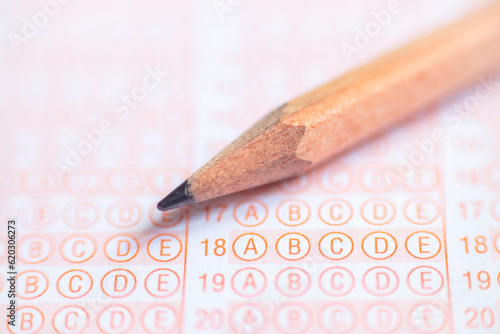 School Students hands taking exams, writing examination holding pencil on optical form of standardized test with answers sheet doing final exam in classroom. Education assessment Concept. Stock photo 