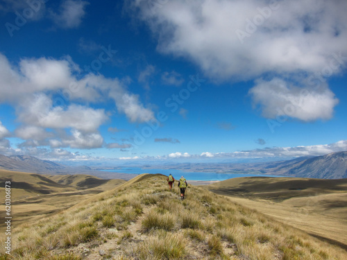 Long distance Hikers on a beatiful ridgeline in New Zealand with Lake Tekapo at the horizon