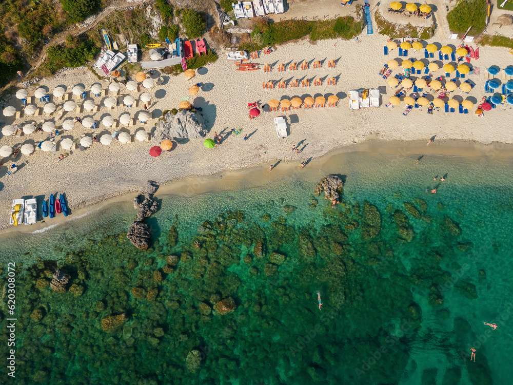 Italy, July 2023: aerial view from the drone of a crystalline Caribbean sea with bathers and beach umbrellas at Grotticelle locality near Capo Vaticano, Tropea, Calabria
