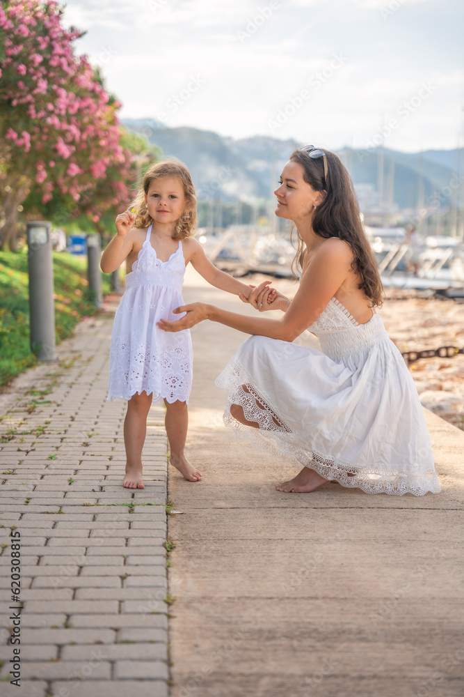 Happy mother and daughter child having fun on luxury yachts on background in marina. Family travel, lifestyle, vacation concept Happy mother and daughter child having fun on luxury yachts on background in marina. Family travel, lifestyle, vacation concept