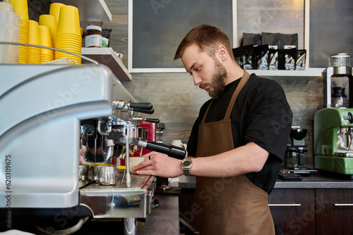 Young male barista preparing coffee in coffee shop