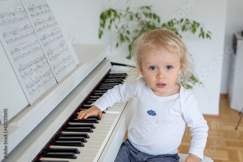 little child playing piano and looking to the camera